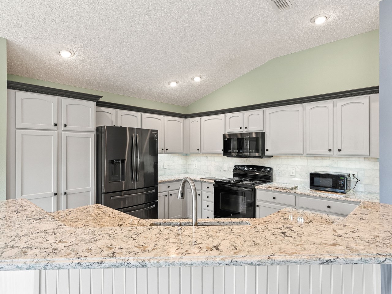 large kitchen quartz counters and black stainless appliances adorn this spacious kitchen. the center island provides a bar height counter.